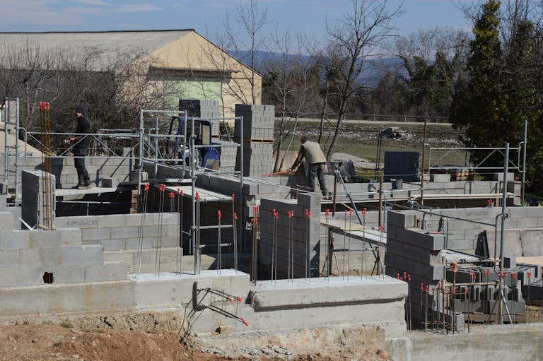 Construction workers building a concrete structure at a sunlit site.