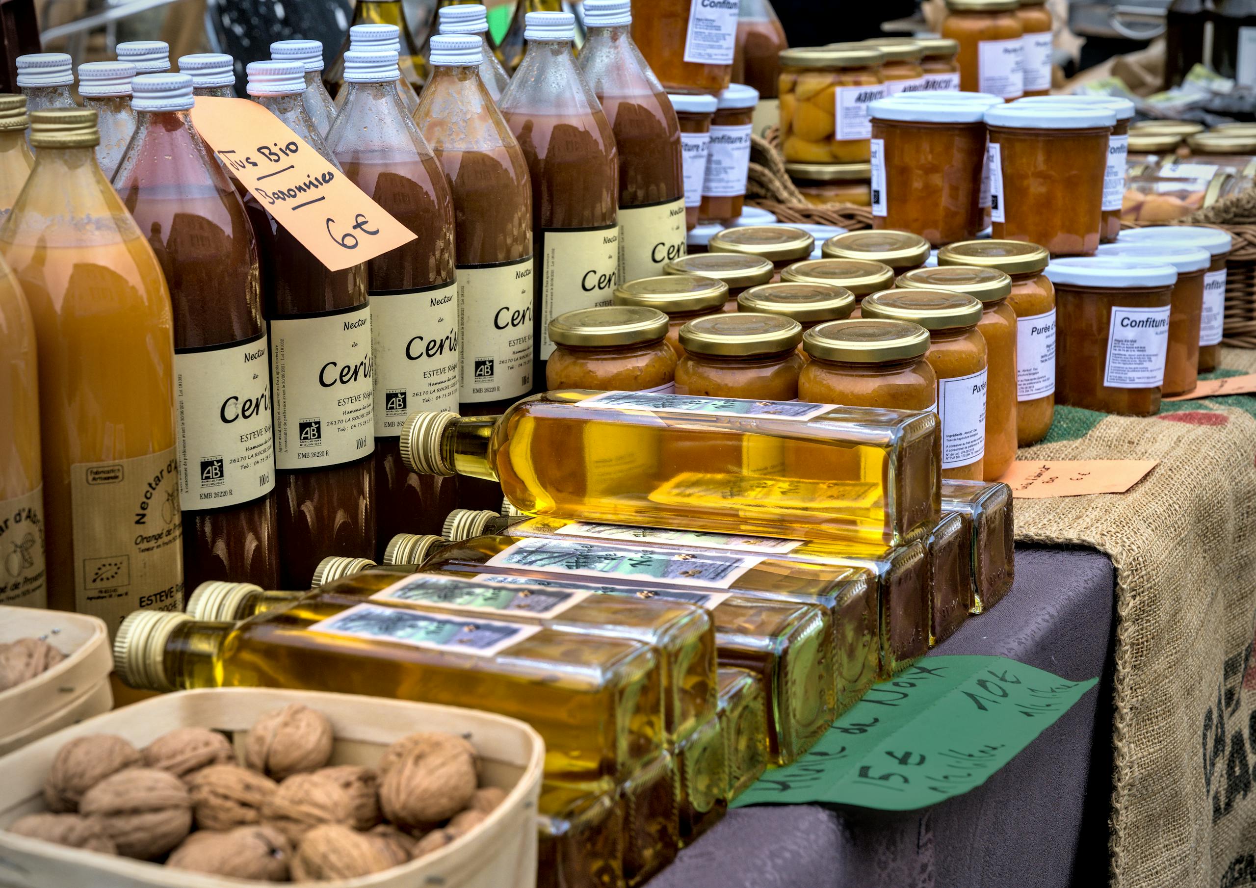 Fresh organic juices, oils, and preserves displayed at a vibrant French market stall.
