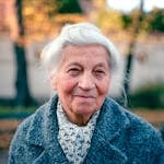 Portrait of a smiling elderly woman outdoors in Kraków during fall.
