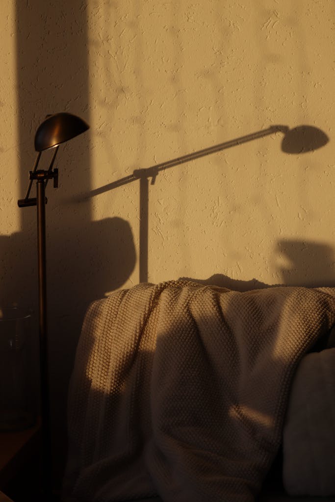 Warm evening light casting shadows on a cozy living room with a modern lamp.