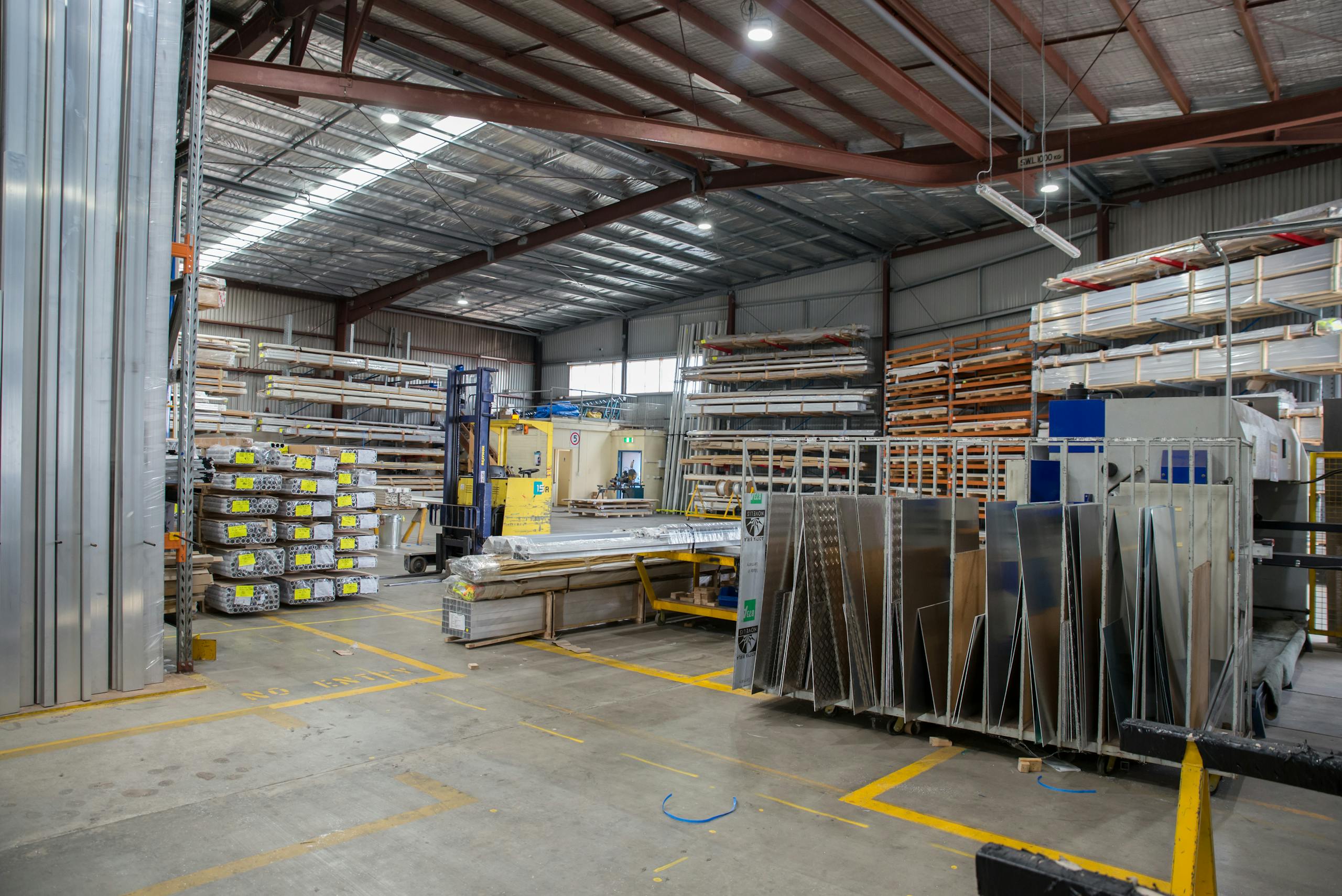 Wide view of an industrial warehouse interior showcasing stacks of steel and metal sheets.